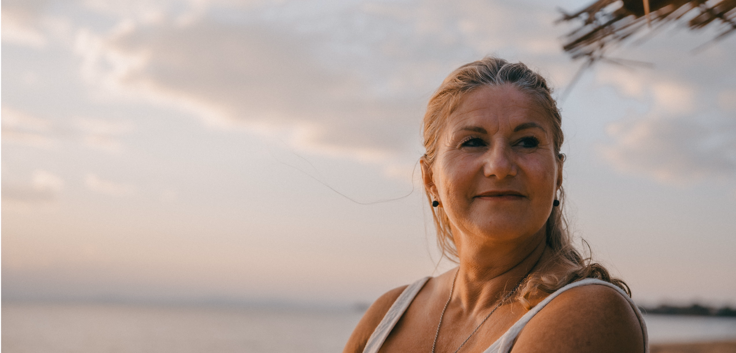 Weise lächelnde Frau vor einem Sonnenuntergang am Strand der Entspannend und beruhigend wirkt