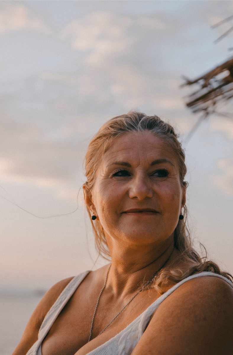 Weise lächelnde Frau vor einem Sonnenuntergang am Strand der Entspannend und beruhigend wirkt
